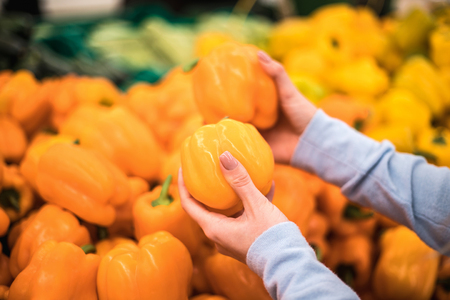 Young woman choose fresh pepper at supermarket, hand close up.の写真素材