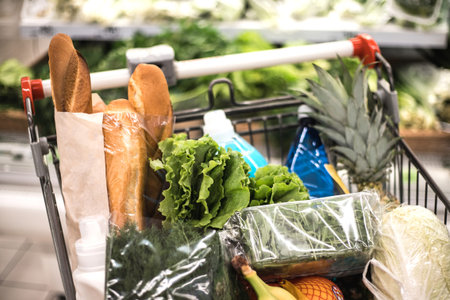 Full of products shopping grocery cart in supermarket.