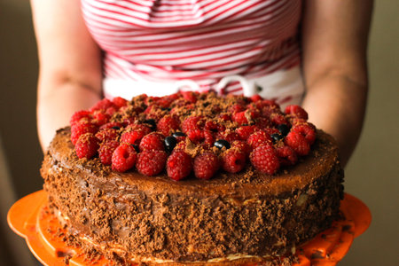 Womans hands holding Birthday cake with fresh berries at home.