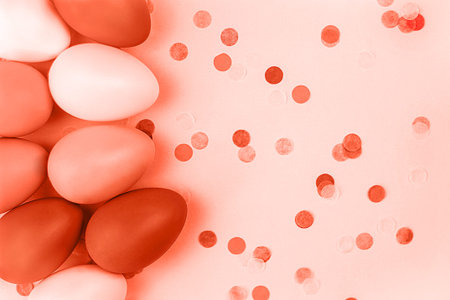 Coral Easter eggs on pink background with confetti. Flat lay.