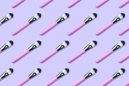 Pattern made from make up brushes on violet background. Minimalism and beauty concept.の写真素材