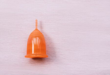 Orange menstrual cup on a pink background. Close up.の写真素材