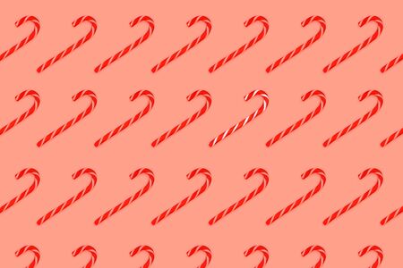 Pattern made from Christmas candy canes isolated on coral background. Christmas holiday concept.の写真素材