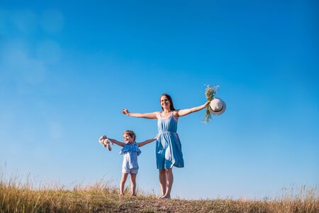 Young mother and daughter have fun and playing in a golden field of sunshine while on a summer holiday. Family activities and outdoors concept.の写真素材