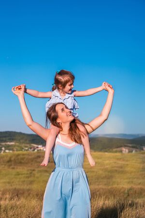 Young mother and daughter have fun and playing in a golden field of sunshine while on a summer holiday. Family activities and outdoors concept.の写真素材