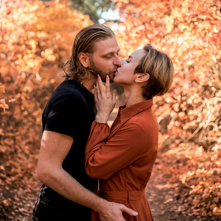 Beautiful young couple in love hugging and kissingg in the autumn forest.