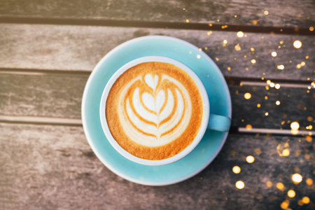 Cappuccino with frothy foam, blue coffee cup top view closeup on gray wooden background. Flat lay...