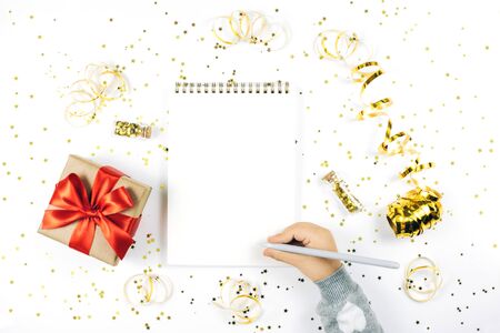 Child's hand writing in notebook on white rustic sparkling background, flat lay style. Christmas planning concept.の写真素材