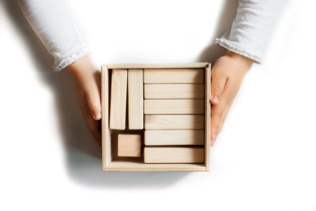 Little girl cleaning up the toy box at home. Child's space organization. Child's hands with toy box isolated on white background.の写真素材