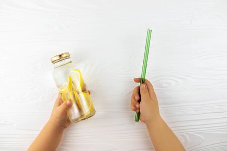 Childs hands holding glass bottle with lemonade and straw. Zero waste concept.の写真素材