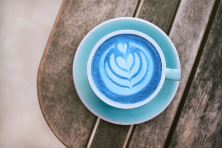Fresh blue matcha with frothy foam, blue coffee cup top view closeup on gray wooden background. Flat lay style.の写真素材