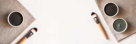 Banner made from set of natural cosmetic black and blue facial masks in ceramic bowls on white...