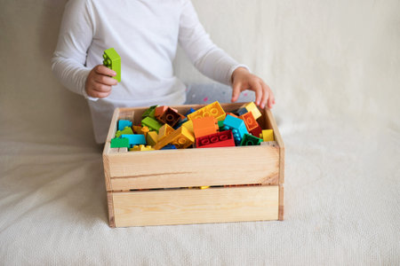 Little girl cleaning up the toy box at home. Child's space organization.