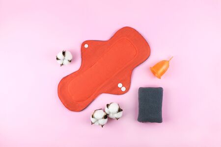Reusable cotton cloth woman pad and menstrual cup on pink background. Top view.の写真素材