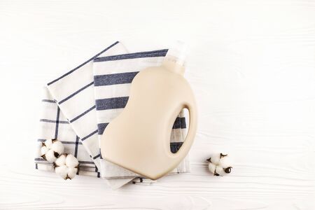 Gel for laundry washing in plastic bottle near a pile of fresh towels. Composition on white wooden background. Flat lay style.の写真素材