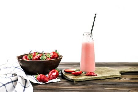 Bottle with fresh strawberry smoothie and fresh strawberries on wooden background isolated on white. Healthy food and drink concept.の写真素材