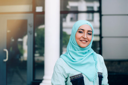 Portrait of beautiful muslim woman at street. Woman wearing hijab in the lights of sun outdoor.
