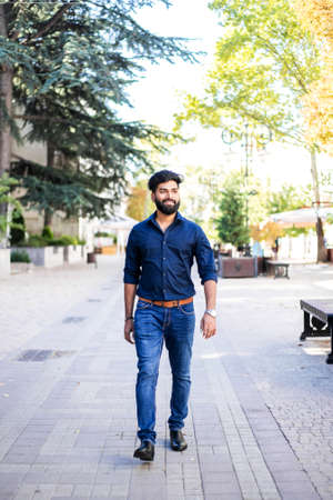 Young Indian man walking in the city street at autumn.の写真素材