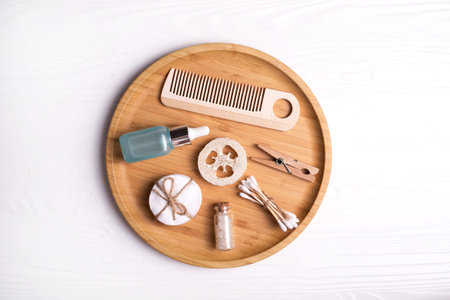 Set of natural cosmetics - cotton pads and swabs, loofah, sea salt and bottle with serum on wooden...
