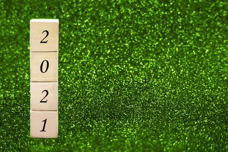 reWooden cubes with numbers 2021 on green sparkling background. Copy space. Festive concept.