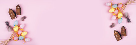 Banner made from colorful Easter eggs over pink background. Top view with copy space
