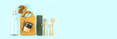 Banner made from eco bags with bamboo cutlery, reusable coffee mug and water bottle on blue...