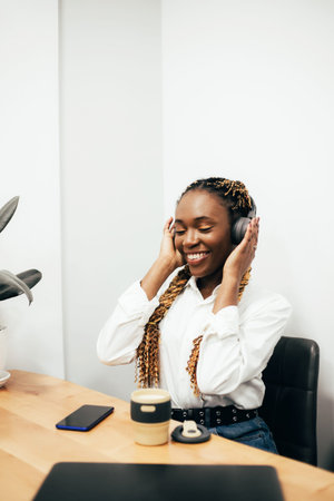 Smiling black girl working and listening to music at cafe.の写真素材