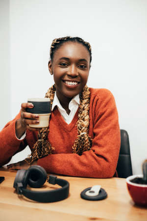 Smiling black girl drinking coffe from reusable cup at cafe.の写真素材