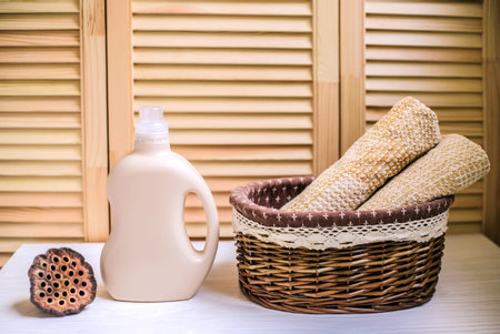Detergents bottle near a pile of towels in basket.