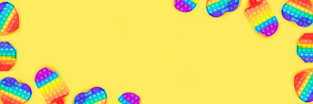 Banner made from multicolored pop it toys isolated on yellow background.の写真素材
