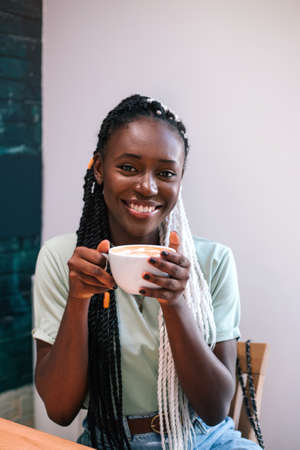 Young black girl drinking her coffee at cafe.の写真素材