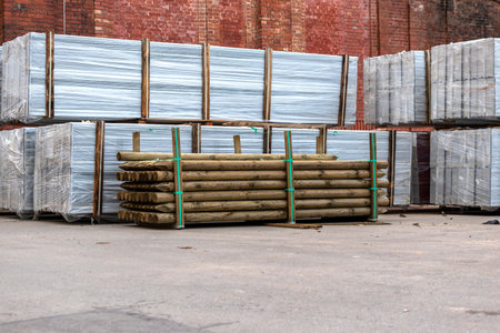 Material for protective wall stacked in the yard. Heaps of wooden fence posts, white protective fence panels.の写真素材