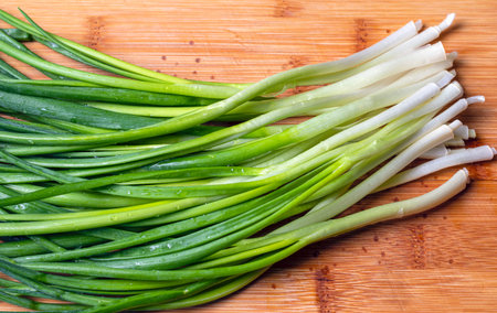 Top view of green spring onions on wooden background.