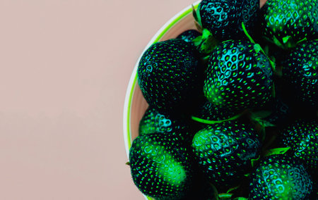Unusually black green color strawberries on pink background.