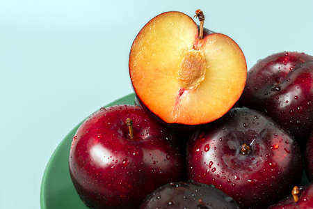 View from side of big red plums on green plate.の写真素材