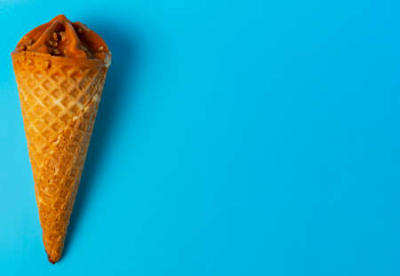 Flat lay of cone caramel ice cream on blue bright background.の写真素材