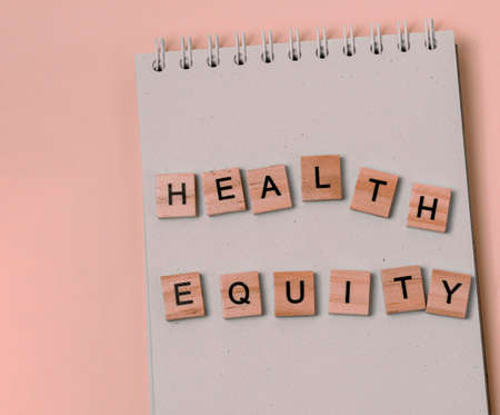 Note health equity with wooden letters on notebook in pink.の写真素材