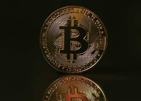 Bitcoin coin on black background with reflection on it.