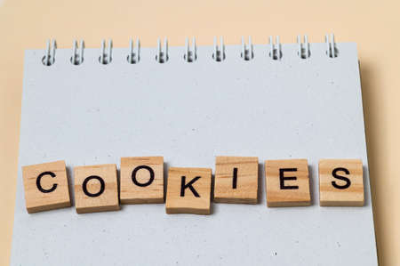 Top view of message Cookies with wooden letters on notebook on yellow background.の写真素材