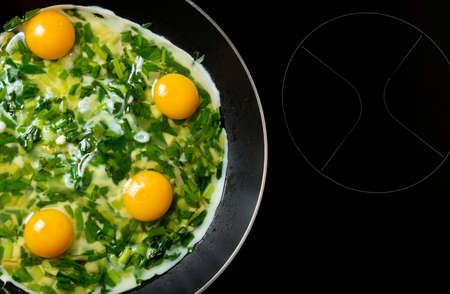View from above of scrambled eggs with green spring onions in the pan.の写真素材