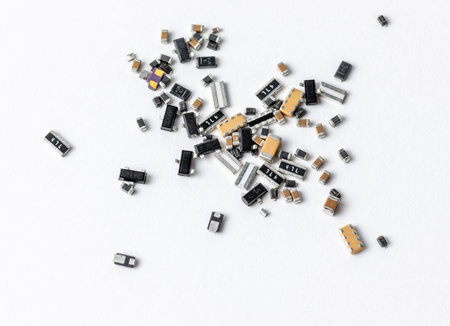 Scattered surface-mount electronic components photographed close-up on a white background, showing...