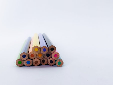 Ends of various colorful pencils in a stack in shallow focus on white background