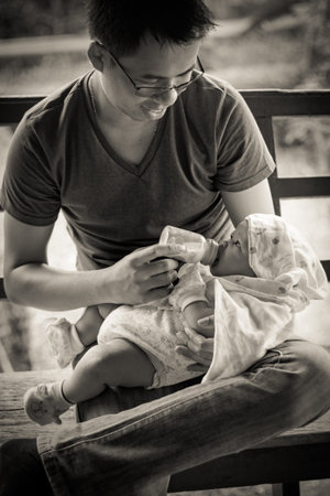 BANGKOK, THAILAND - AUGUST 2014: Asian Thai man Feeding a Newborn Baby on 31 August 2014のeditorial素材