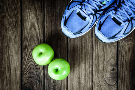 Sport shoes and apples  on a  wooden background. Sport equipment, healthy and active lifestyles, copy space for text. Conceptual photo. Top viewの写真素材