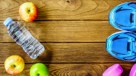 Fitness, healthy and active lifestyles Concept, Bottle of water, dumbbells, sport shoes and apples on wood background. copy space for text.  Top viewの写真素材