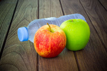 Healthy eating concept, bottle of water, fresh red and green apples on the wooden tableの写真素材
