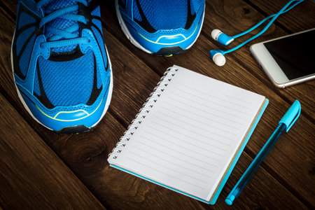 Fitness, healthy and active lifestyles Concept, sport shoes, smartphone with earphone, and blank notebook on wooden background. copy space for text. Top viewの写真素材