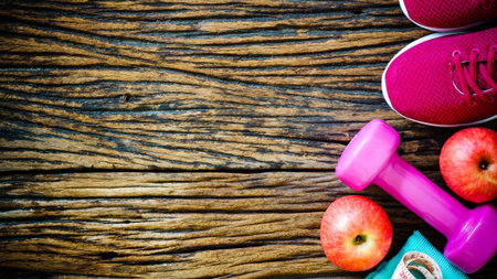 Fitness, healthy eating and active lifestyles Concept, dumbbells, sport shoes, apples, measuring tape, towel, jump rope and headphone on wood background. top view with copy space for text.の写真素材