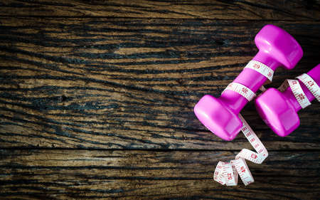 dumbbell and measuring tape  on wooden background,Sport equipment,Healthy lifestyle concept,Still life photography, Top view with copy spaceの写真素材