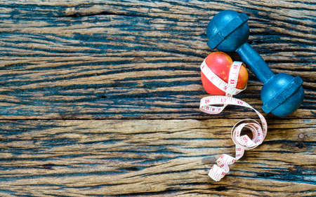 dumbbell and measuring tape and red heart on wooden background,Sport equipment,Healthy lifestyle concept,Still life photography, Top view with copy spaceの写真素材